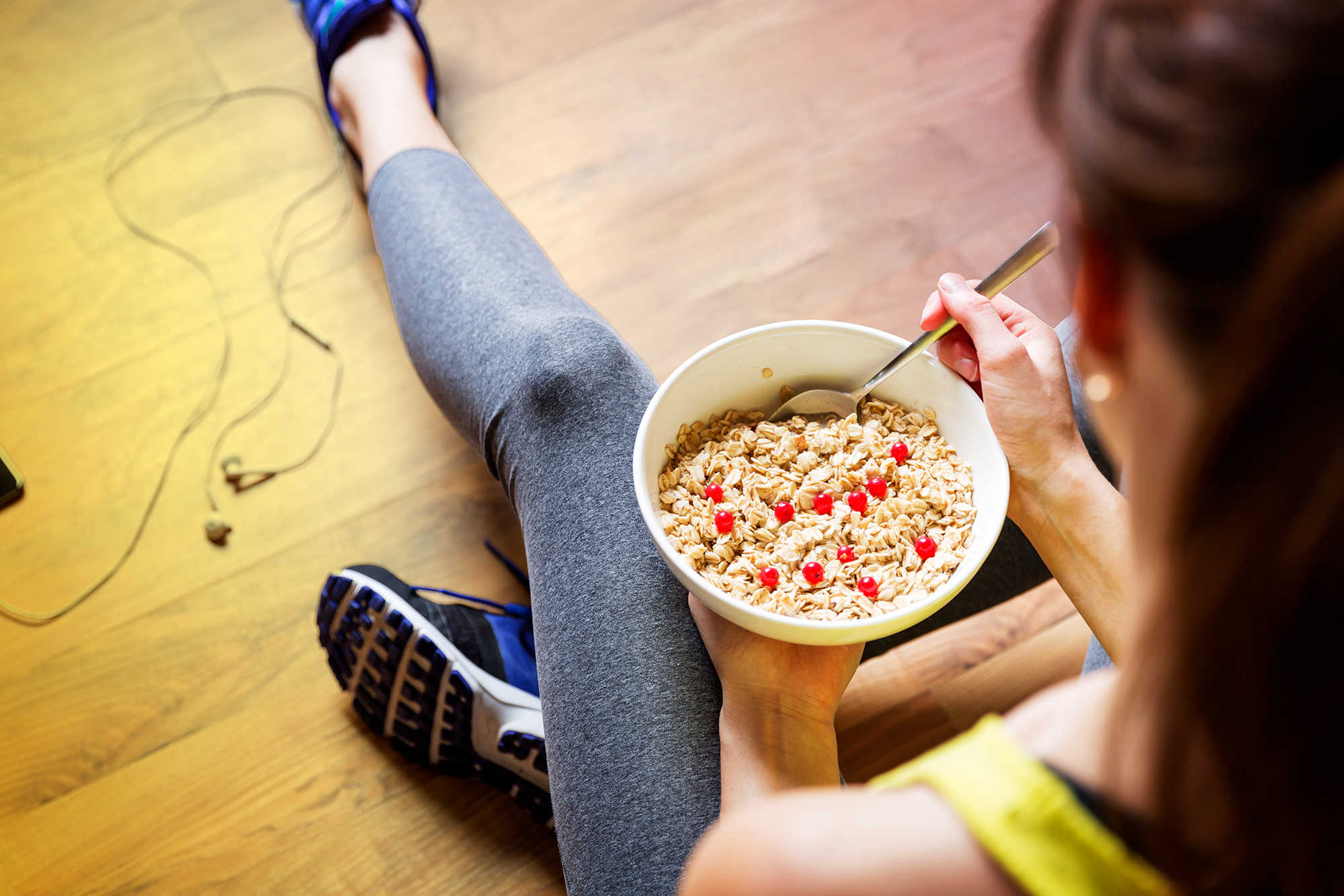 Young girl eating a oatmeal with berries after a workout . Fitness and healthy lifestyle concept.